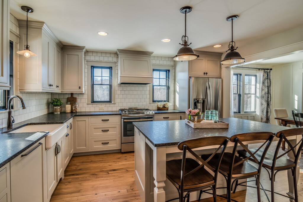 Custom kitchen remodel featuring white shaker cabinets, black countertops, subway tile backsplash, stainless steel appliances, and a large island.
