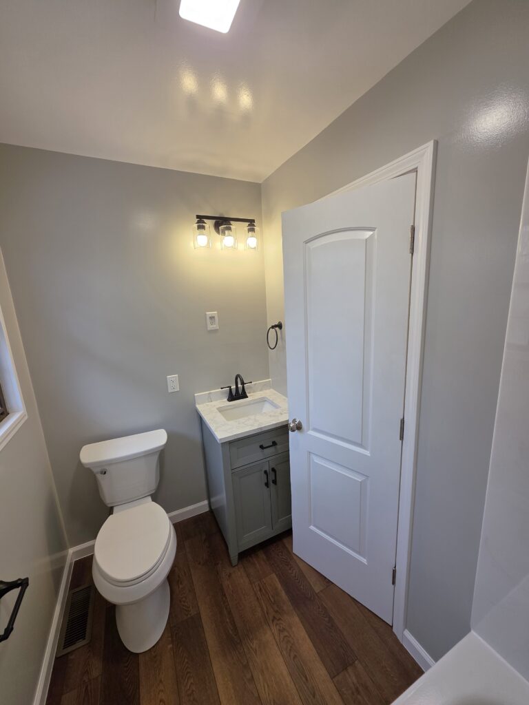After photo of bathroom remodel in Wadesville Indiana featuring new vanity, modern lighting, updated flooring, and fresh paint